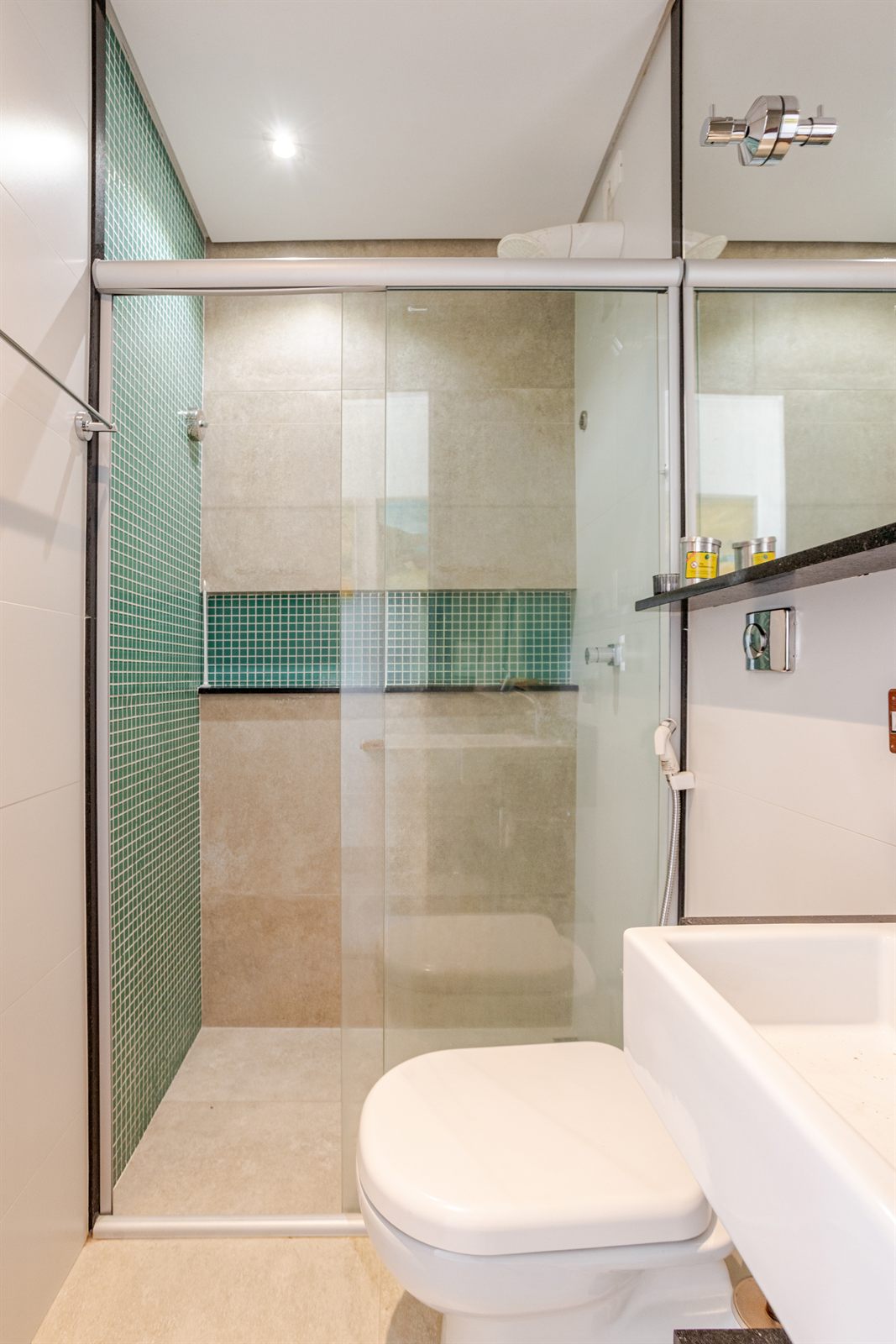 Banheiro com box de vidro e pastilhas verdes