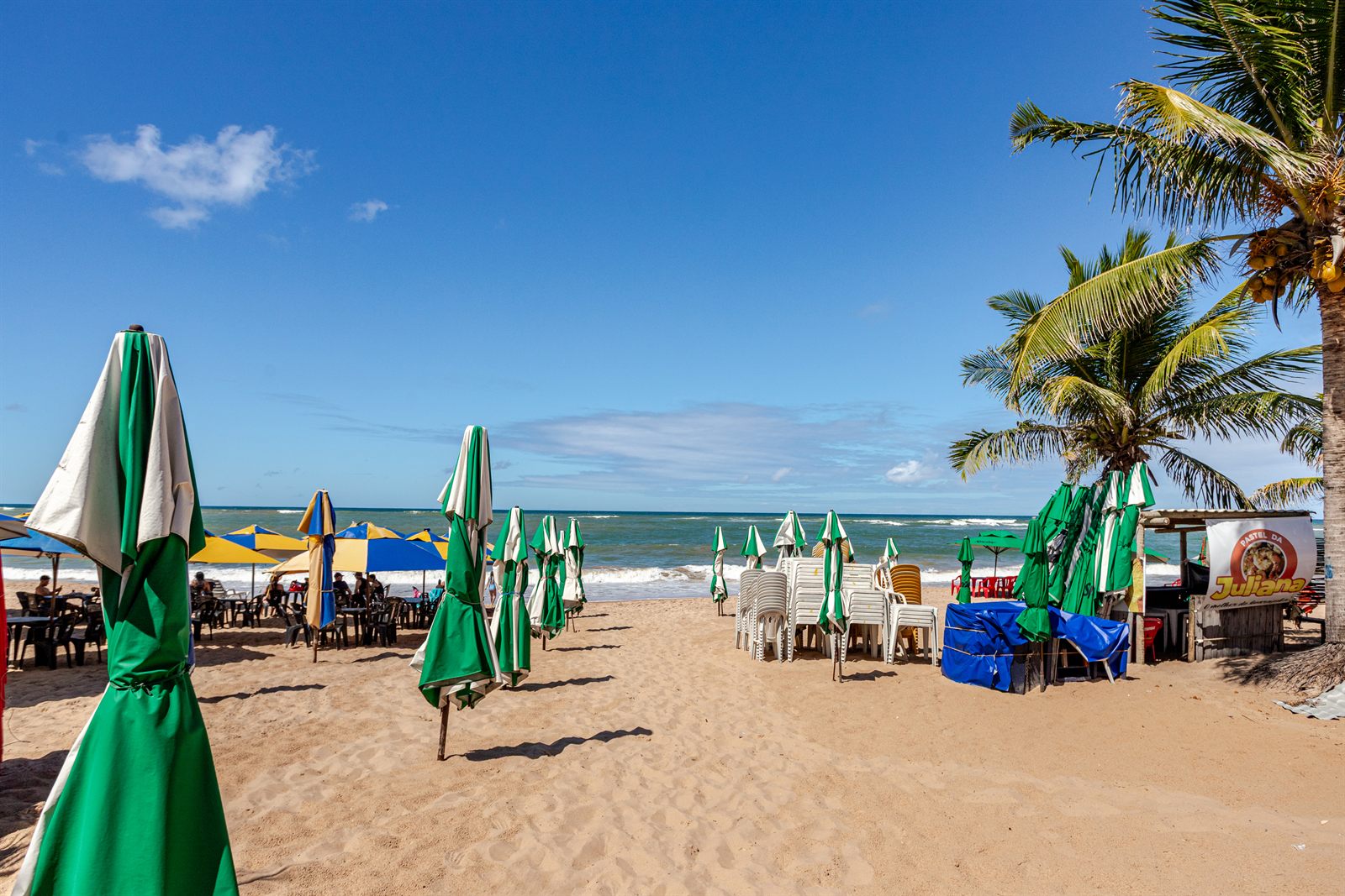 A praia em frente ao condomínio, com o mar e coqueiros
