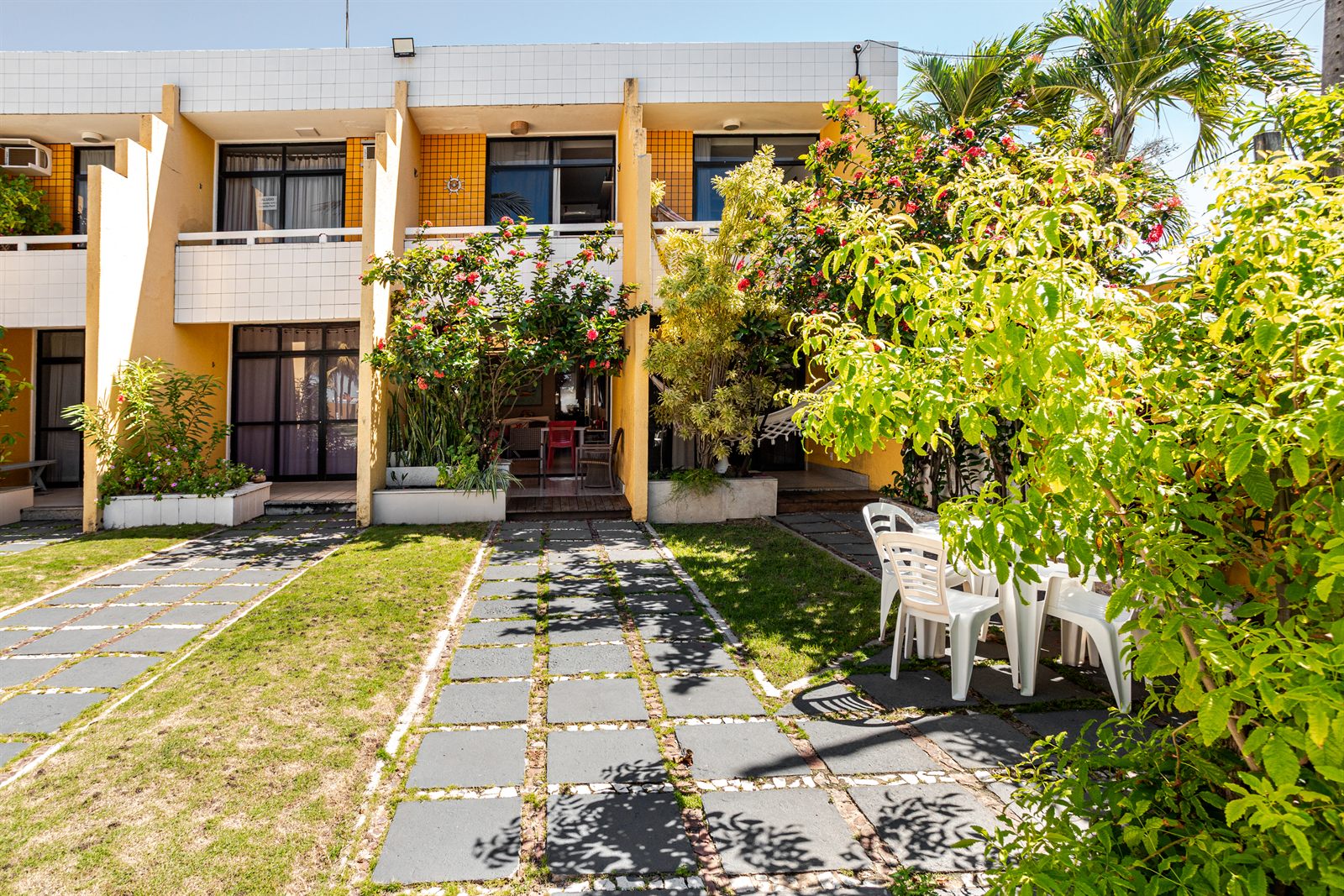 Jardim interno do condomínio com flores e área de convivência